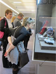 A group of people standing and  looking at a Swiss Packaging designed Basel Fair exhibit stand Jewelry display 