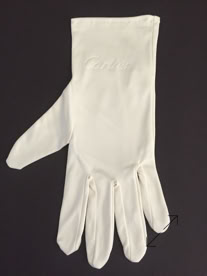 A single white Cartier jewelers glove with a smooth texture, displayed on a dark background manufactured by Swiss Packaging of New York and Switzerland