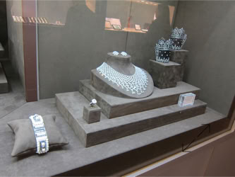 Basel Display Case A jewelry display case featuring a necklace, earrings, a bracelet, and a ring on a cushioned stand; the exhibit stand and displays designed by Swiss packaging of New York and Switzerland