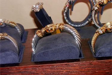 Display of David Yurman watches with rigid bracelets with twisted metal designs and gold accents on dark cushioned stands design and manufactured by Swiss Packaging of New York and Switzerland