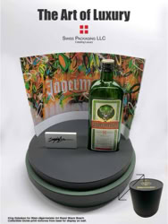 ArtBasel Miami Display for Jägermeister. A green Jägermeister bottle on a diplay base and colorful Limited edtion collector print in the back of the display. Text at the top of the ad reads "The Art of Luxury" with a logo beneath it manufactured by Swiss Packaging of New York and Switzerland