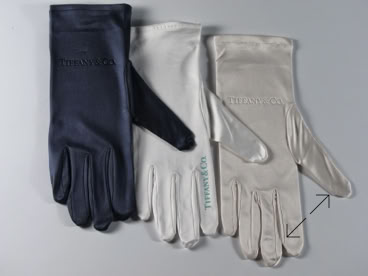 Three pairs of jewelers gloves in different colors: dark blue, white, and light gray, arranged side by side on a flat surface manufactured by Swiss Packaging of New York and Switzerland