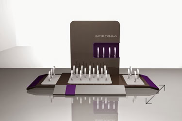 A David Yurman watchdisplay stand with multiple rows of cylindrical objects, featuring a brown and purple color scheme, set on a reflective surface design by Swiss Packaging of New York and Switzerland