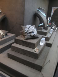 Basel Display Case A glass display case containing various pieces of jewelry, including necklaces and rings, with people visible in the background design of the trade show booth and displays by Swiss Packaging of New York and Switzerland