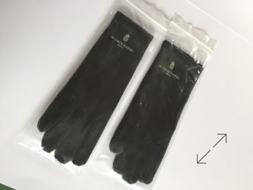 Two pairs of black jewelers gloves in transparent plastic packaging on a white surface manufactured by Swiss Packaging of New York and Switzerland