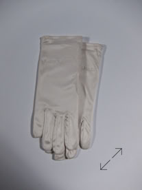 A pair of white jewelers gloves placed on a light gray surface manufactured by Swiss Packaging of New York and Switzerland