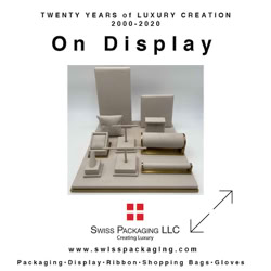 Display of various white packaging items on a platform with text above and below, including "On Display" and "Swiss Packaging LLC."