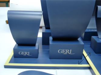 Blue display stands with the word "GERL" printed on them, featuring curved surfaces and rectangular bases designed and manufactured by Swiss Packaging of New York and Switzerland