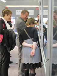A group of people standing and  looking at a Swiss Packaging designed Basel Fair exhibit stand Jewelry display 