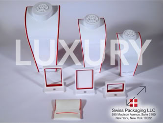 Jewelry display stands and holders with red accents, arranged on a surface with the word "LUXURY" overlaid manufactured by Swiss Packaging of New York and Switzerland