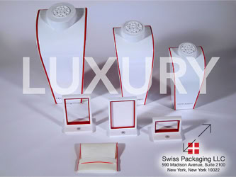 Jewelry display stands and holders with red trim, arranged in two rows, with the word "LUXURY" overlaid manufactured by Swiss Packaging of New York and Switzerland