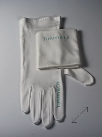 White Tiffany and Co. jewelers gloves with text on the cuffs, placed on a flat surface manufactured by Swiss Packaging of New York and Switzerland